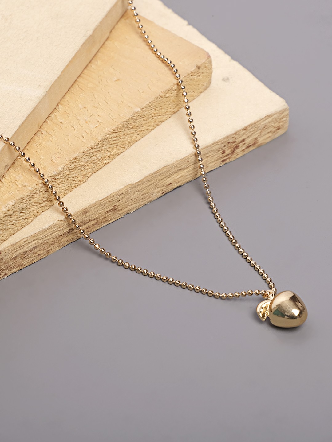 gold tonned necklace with golden apple pendant